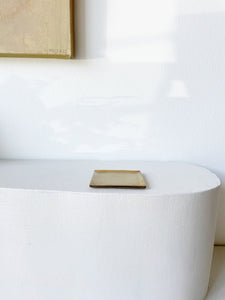 brass square plate on white pedestal 