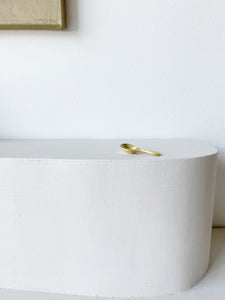 single brass tea scoop on white pedestal