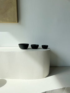 three black cast iron bowls sitting in a row on a white ledge