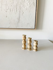 trio of hand carved ambrosia maple candleholders in varying heights sitting on a white countertop