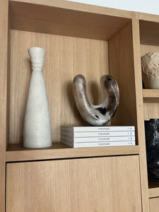 Styled photo of Ceramics sculptures and books on a custom built shelving unit.