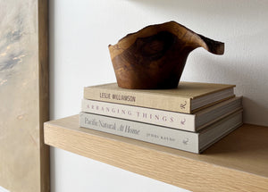 stack of books with a wooden bowl atop.